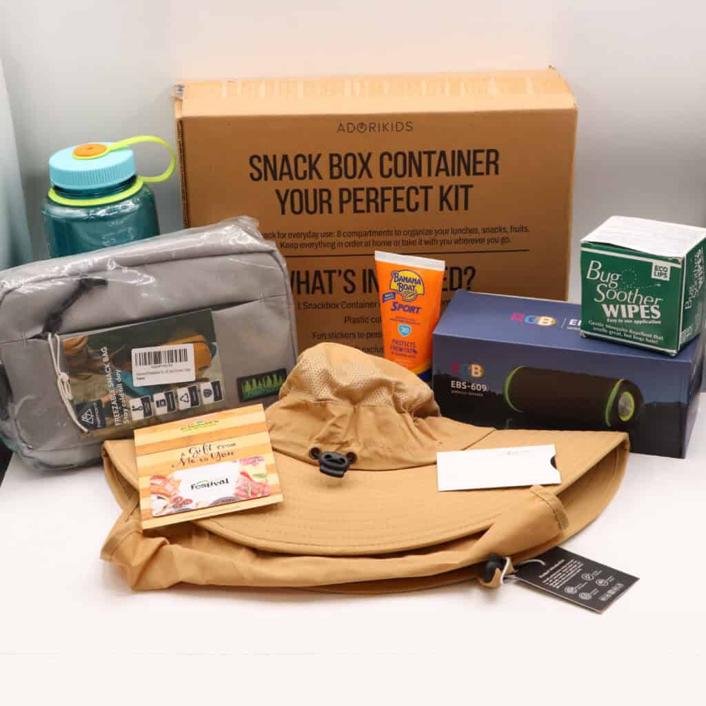 Items to enjoy the outdoors including a hat, water bottle, bug wipes, sunscreen, snacks, and a speaker