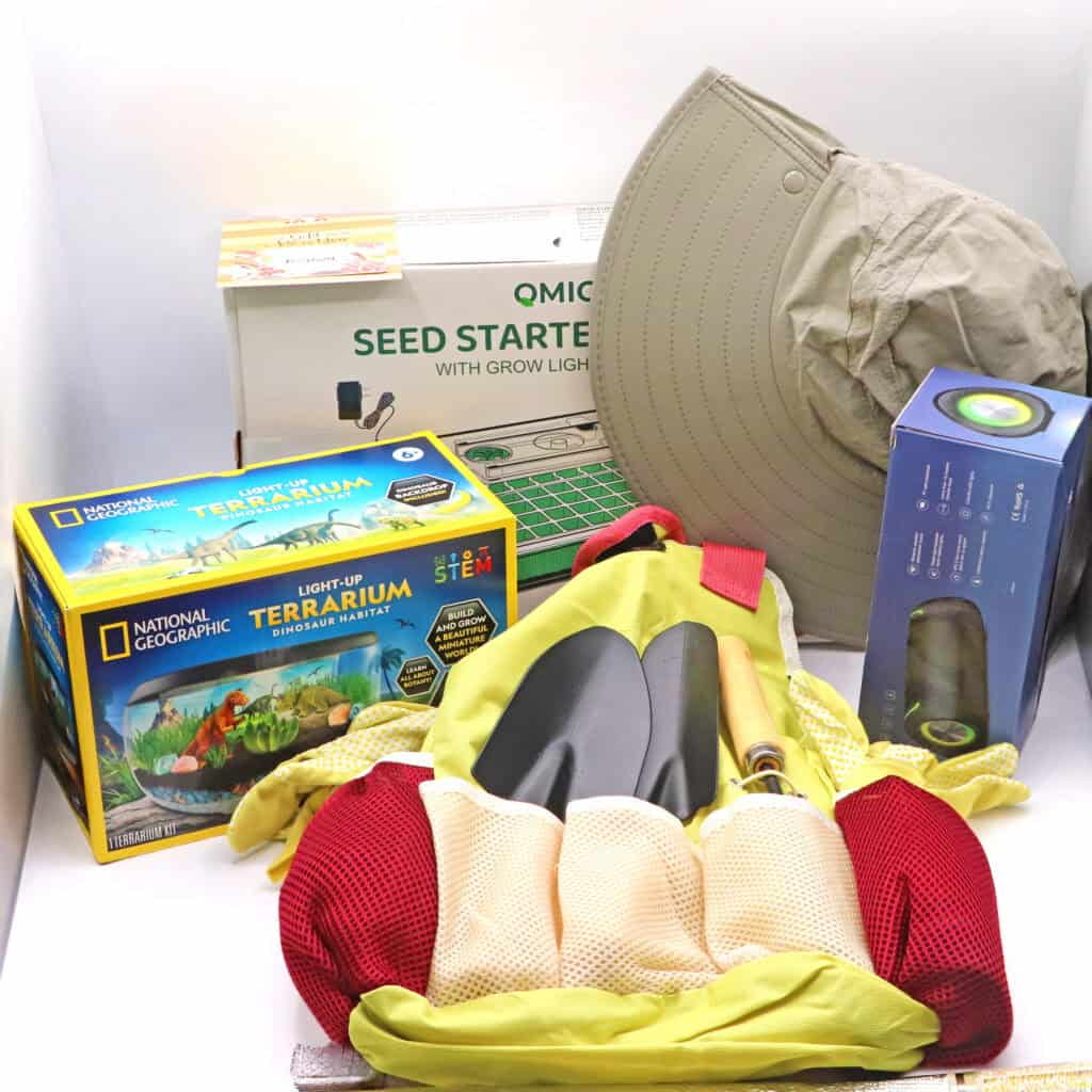 A variety of gardening items including a hat, shovels and tool belt, terrarium, speaker, and seed starter.